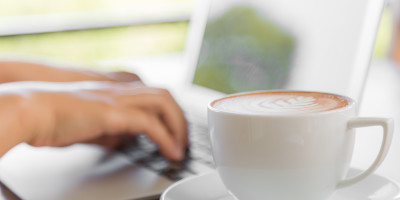 Closeup of business woman hand typing on laptop keyboard and coffee
