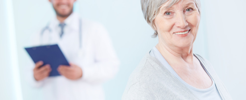 Senior patient looking at camera with doctor on background