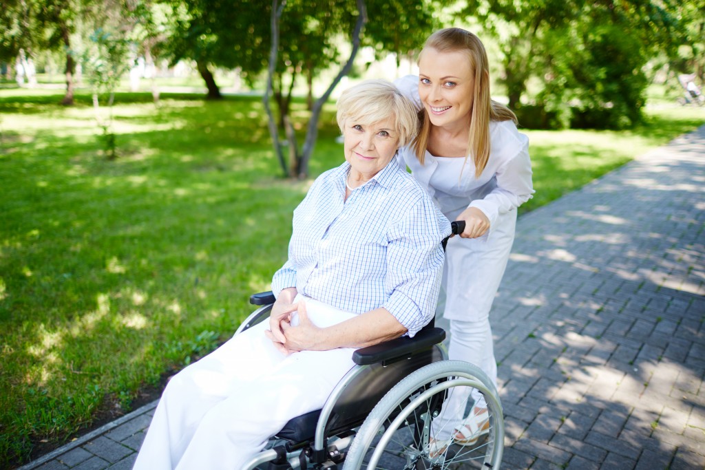 Female caregiver walking with senior patient in park