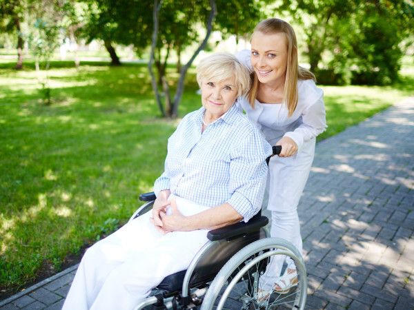 Female caregiver walking with senior patient in park